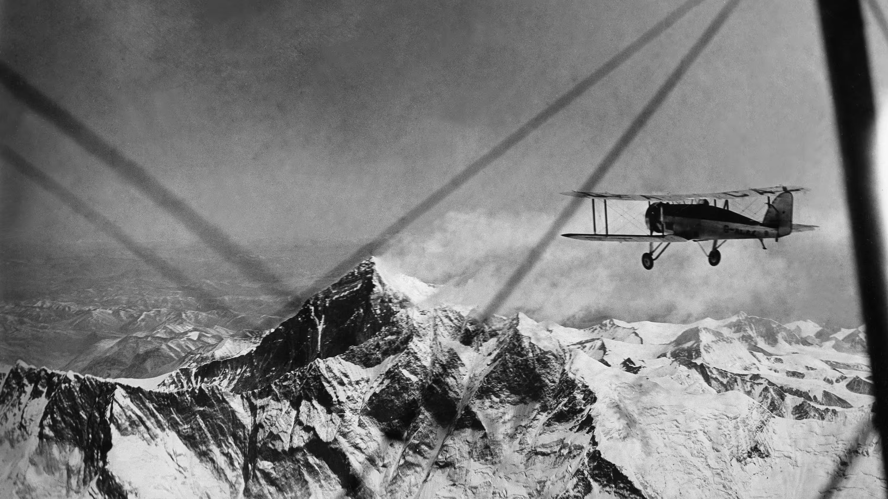 Biplane flying over snow-capped mountains